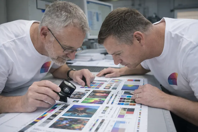 Two print specialists checking a printed proof